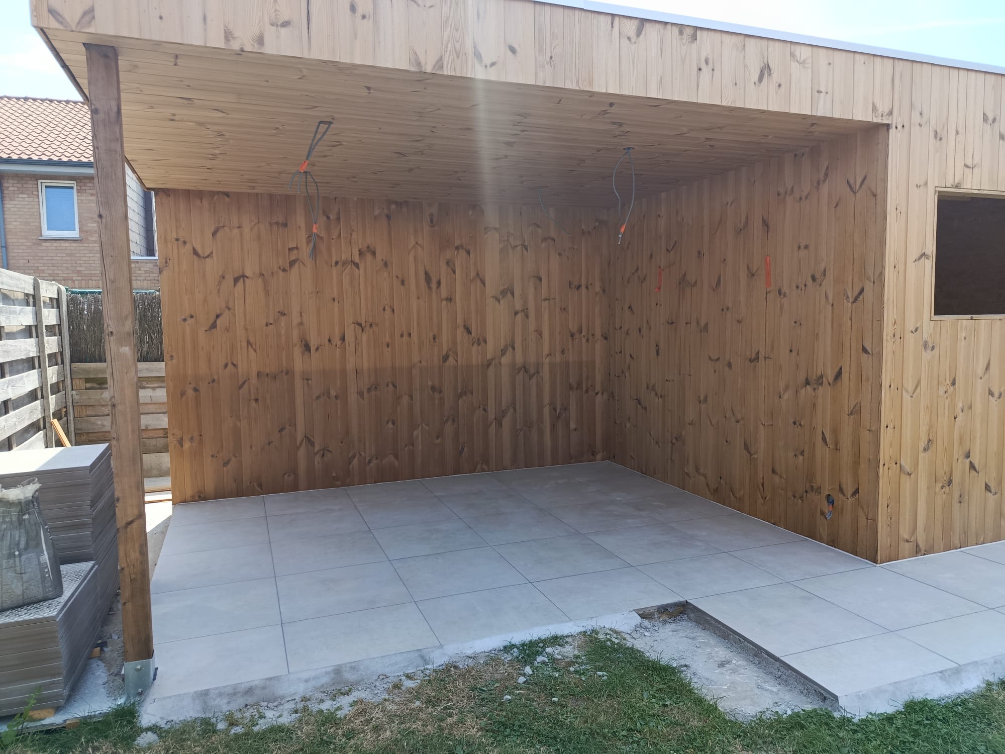 Overdekte terrasconstructie in hout met een strak gelegde tegelvloer